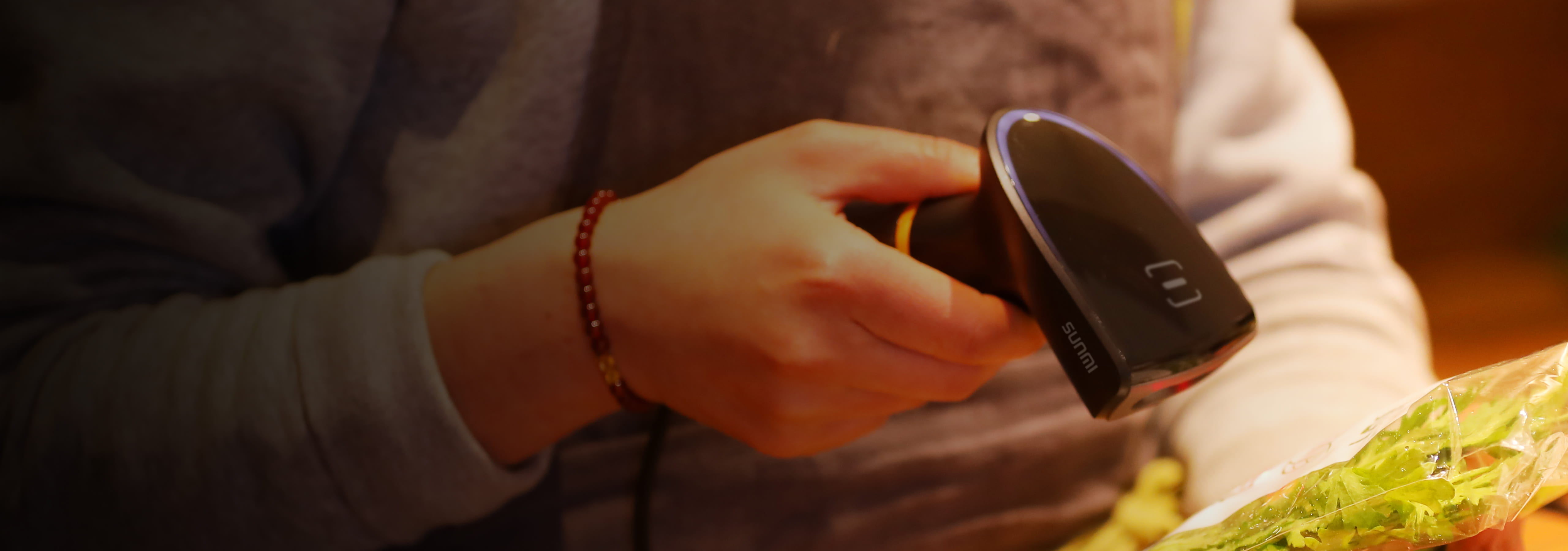 Staff using the Sunmi handheld scanner to scan a product barcode at the counter
